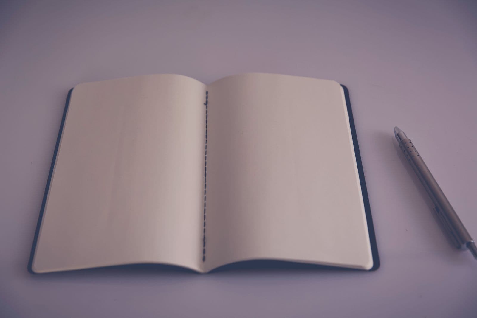 An open, blank notebook with a pencil beside it